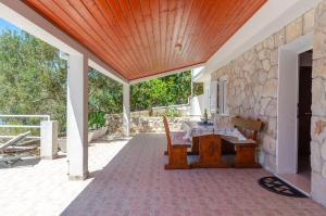 a patio with a table and a stone wall at Apartmani Srdjana in Prizba