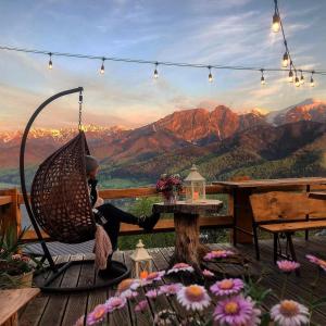 una persona sentada en una silla de mimbre en una terraza con vistas en Dom Tatrzański Ewa, en Kościelisko