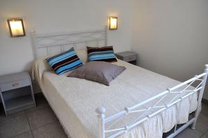 een wit bed met kussens in een slaapkamer bij Residence de tourisme Le clos des Vendanges in Moriani Plage