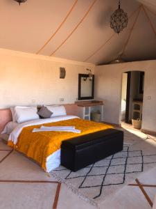 una camera da letto con un letto grande con una coperta arancione di Mhamid Luxury Camp Experience a M'Hamid