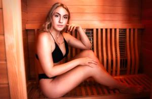 a woman sitting on a bench in a sauna at Auberge Hotel Spa Watel in Sainte-Agathe-des-Monts