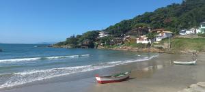 a beach with two boats on the sand and houses at Pousada Moradas da Praia in Garopaba