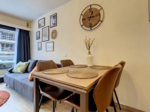 a dining room table with chairs and a clock on the wall at Studio enjoy 55 in Nieuwpoort