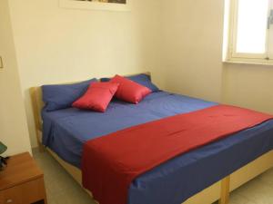 Bett mit zwei roten Kissen auf einem Zimmer in der Unterkunft Casa Luigi a 400m Dalla Sabbia in Lido Marini