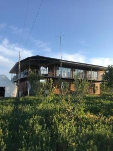 a large building with a balcony in a field at Guest house and yurt camp "Aktan" in Bokonbayevo