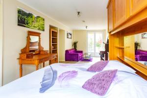 a bedroom with a bed with purple pillows and a piano at Apakabar Homestay, Gîte 6 personnes, proche gare Melun, parking privé in La Rochette