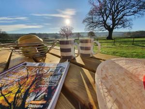 a table with two coffee cups and a magazine at The Victorian Barn, Self-Catering Holidays with Pool and Hot Tubs, Dorset in Woolland