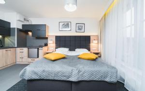 sypialnia z dużym łóżkiem z 2 żółtymi poduszkami w obiekcie Aron Residence - by Upstairs w Krakowie