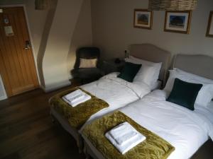 1 dormitorio con 2 camas y almohadas verdes y blancas en The Fox and Hounds en Whittlebury