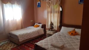 a bedroom with two beds and a window at Hotel Trans Sahara Merzouga in Merzouga