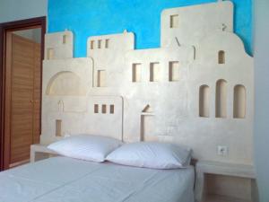 ein Bett mit einem weißen Kopfteil mit Gebäuden darauf in der Unterkunft Foinikas Studios in Mérikhas