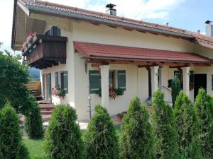 uma casa com varanda e arbustos em frente em Ferienwohnung Heimat em Grassau