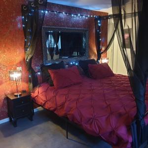 1 dormitorio con cama con edredón rojo y luces en Les Nuances de Mélis', en Crémieu