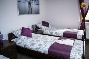 2 camas en una habitación con sábanas moradas y blancas en Rezydencja Bakamus, en Sandomierz