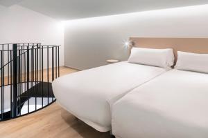 a white bed sitting in a room next to a wall at B&B Hotel Málaga Centro in Málaga