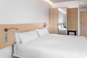 um quarto com uma cama branca e um espelho em B&B HOTEL Málaga Centro em Málaga