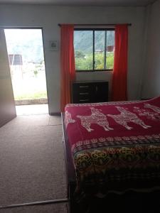 una camera da letto con un letto e una finestra con tende rosse di Montano Camping & Hostel a Baños