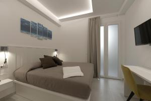 a bedroom with a bed and a desk and a television at Isule Apartments in San Vito lo Capo