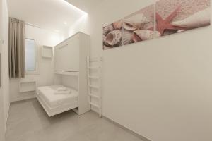 a small white room with a bed and a painting at Isule Apartments in San Vito lo Capo