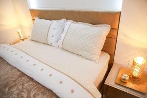 - un lit avec des oreillers blancs et une table avec une lampe dans l'établissement Lux Apartman AS, à Žabljak