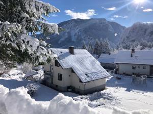 a house covered in snow with mountains in the background at SavaDolinka House in Mojstrana