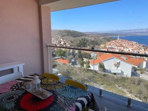 a balcony with a table and a view of a city at Apartman Zoe Vrbnik in Vrbnik
