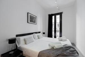 a white bedroom with a large bed and a window at Decô Apartments Barcelona-Eixample in Barcelona
