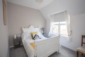 a white bedroom with a bed and a window at Foresters Cottage in Worthing