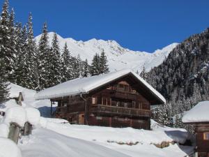 una baita di tronchi nella neve con montagne sullo sfondo di Gallfallalm a Santa Maddalena in Casies Valbassa