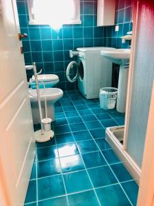 La salle de bains est pourvue de carrelage bleu, de toilettes et d'un lavabo. dans l'établissement Residenze Zodiaco, à Santa Teresa Gallura