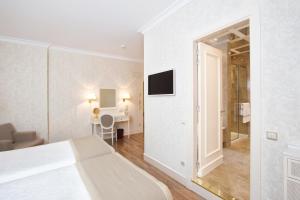 a white bedroom with a bed and a bathroom at Hotel Atlántico in Madrid