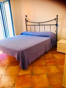 - un lit avec une couverture violette sur du parquet dans l'établissement Residenze Zodiaco, à Santa Teresa Gallura
