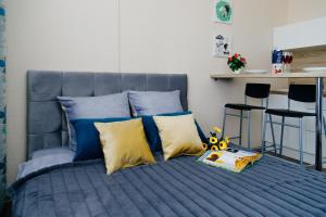 a blue bed with yellow pillows and a book on it at Прекрасная студия ЖК Академ-Риверсайд. in Chelyabinsk