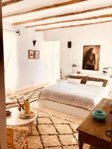 a white bedroom with a large bed and a table at Dar Alya Essaouira Maison et table d'hôtes in Ghazoua