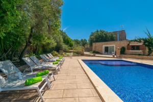 a swimming pool with lounge chairs next to a house at Saran in Llucmajor