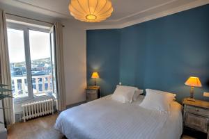 a blue bedroom with a bed and a large window at Hotel Le Rayon Vert in Étretat