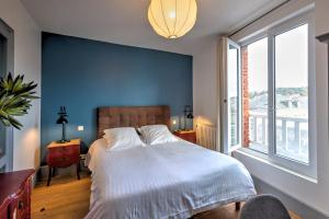 a bedroom with a large bed with a blue wall at Hotel Le Rayon Vert in Étretat