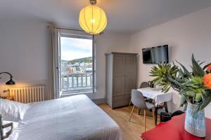 a bedroom with a bed and a table and a window at Hotel Le Rayon Vert in Étretat
