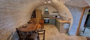 a kitchen with a wooden table in a stone wall at Ferme de Laspeyrières in Montcuq