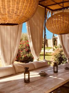 a wooden table with white curtains and lights on it at Dar Alya Essaouira Maison et table d'hôtes in Ghazoua