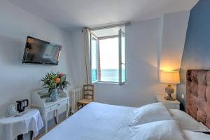 a white bedroom with a bed and a window at Hotel Le Rayon Vert in Étretat