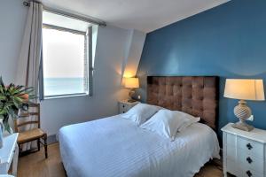 a blue bedroom with a bed and a window at Hotel Le Rayon Vert in Étretat