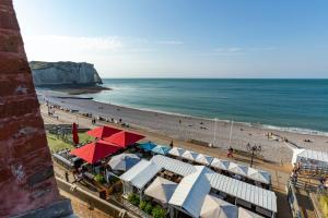 a beach with umbrellas and people on the beach at Hotel Le Rayon Vert in Étretat