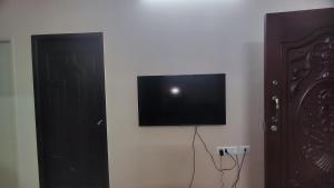 een flatscreen-tv aan een muur naast een deur bij Sumithra Apartment in Pondicherry