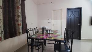 een eettafel met stoelen en een zwarte deur bij Sumithra Apartment in Pondicherry