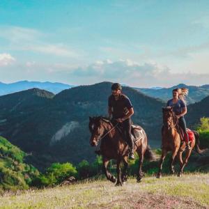 dos personas están montando caballos en las montañas en Re Piano appartamento Le Rondini, en Modigliana