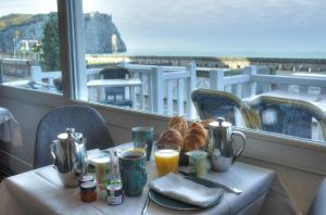 a woman sitting at a table with a cup of coffee at Hotel Le Rayon Vert in Étretat