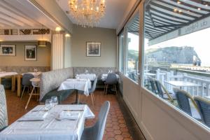 a restaurant with tables and chairs and a chandelier at Hotel Le Rayon Vert in Étretat