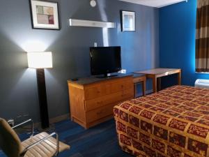 a hotel room with a bed and a flat screen tv at Travel Inn Winter Haven in Winter Haven