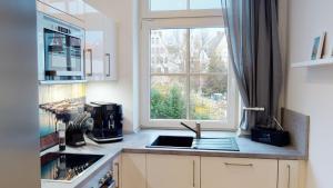 uma cozinha com um lavatório e uma janela em Lieblingsapartment No.3 mit 2 Schlafzimmern in Top City-Lage em Rostock